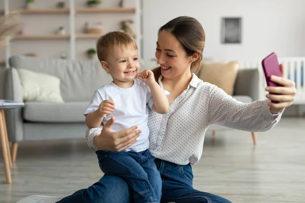 Jovem mãe e seu filho adorável criança ter chamada de vídeo com a família via smartphone, passar o tempo juntos em casa — Fotografia de Stock