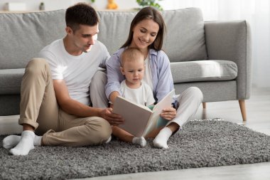 Üç kişilik mutlu bir aile ve küçük oğlu evde birlikte kitap okuyor.