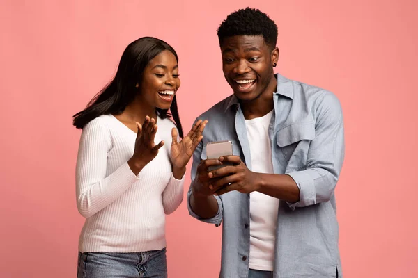 Красивый черный парень показывает своей девушке что-то на смартфоне — стоковое фото