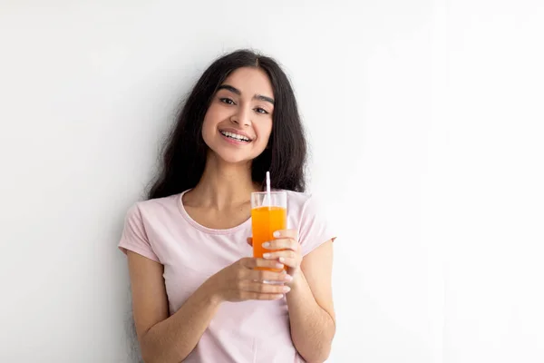 Neşeli genç Hintli kadın elinde bir bardak taze portakal suyu ya da beyaz arka planda mango suyu tutuyor. — Stok fotoğraf