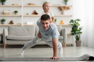 Yurtiçi antreman. Bebek sırtındayken şınav çeken mutlu adam.