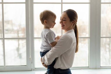 Anneler sever. Küçük oğlunu kucağında tutan genç bir anne. Çocuğa sarılıyor. Pencerenin yanında duruyor.