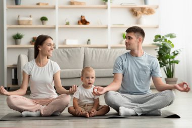 Evde Yoga. Küçük bebek meditasyonu yapan mutlu ve genç bir aile