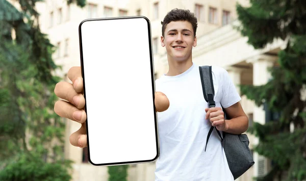Jovem estudante do sexo masculino mostrando branco tela do smartphone vazio, close-up — Fotografia de Stock