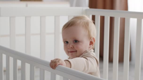 Мила дитина з роєм іграшка в руці стоячи в дитячому ліжку — стокове відео