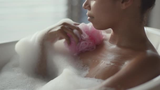 Jovem senhora afro-americana lavando-se com esponja e chuveiro de gel, desfrutando de banho em casa, foco seletivo — Vídeo de Stock
