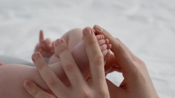 Stimulation du développement du bébé. Mère touchant les petites jambes de son nouveau-né — Video