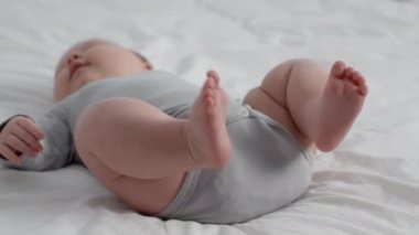 Çocuk Doğumu Konsepti. Tombul Yeni Doğmuş Bebek 'in Yatakta Uzanmış Vücut Giysisi Giydiği Yakın Çekim