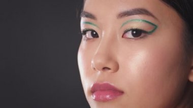 Yaratıcı yeşil okları olan Asyalı genç bir kadının yarı profil portresi kameraya bakıyor, boş alan.