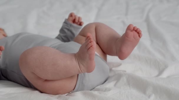 Cuidados diários recém-nascidos. Parte inferior do bebê infantil deitado na cama, close-up — Vídeo de Stock