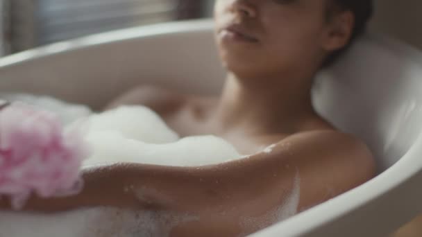 Hygiëne en lichaamsverzorging. jong onherkenbaar Afrikaans amerikaanse vrouw wassen haar lichaam met spons, ontspannen in warm bad — Stockvideo