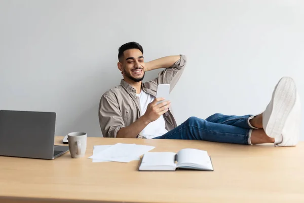 Arabo uomo a riposo piedi sul tavolo utilizzando il telefono cellulare — Foto Stock