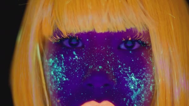 Fantasie make-up. Extreme close-up portret van jonge aziatische dame met gloeiende ruimte make-up kijken naar camera in neon lichten — Stockvideo