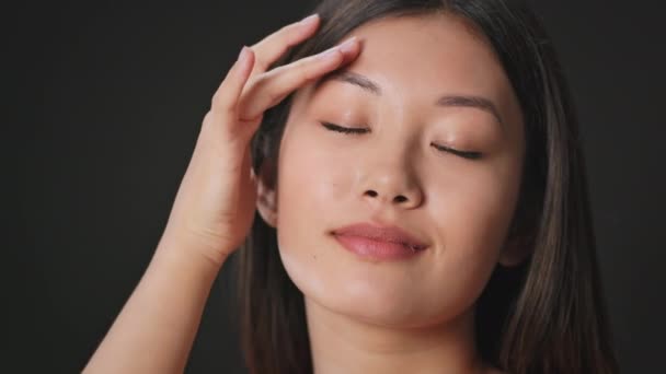 Begreppet kvinnlighet. Ung asiatisk kvinna smeker sitt perfekta ansikte, njuter av sin släta hud, svart bakgrund, tomt utrymme — Stockvideo