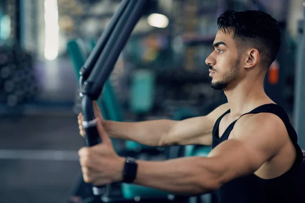 Entraînement confiant de sportif arabe sur la machine de plate-forme de Pec au gymnase, vue latérale — Photo