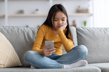 Evde cep telefonu kullanan sıkılmış genç Japon kız.