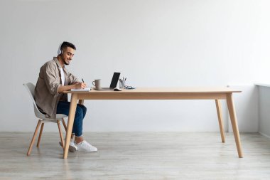 Laptop kullanan ve yazı yazan gülümseyen bir Arap portresi