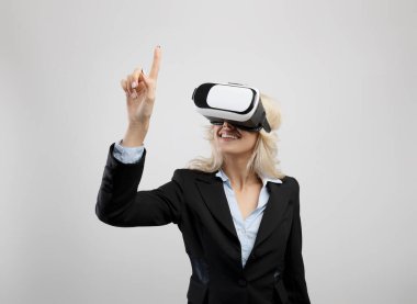 VR kulaklıklı bir iş kadını sanal ekrana dokunuyor, artırılmış gerçekliği keşfediyor, işle ilgili faaliyetlerde bulunuyor.