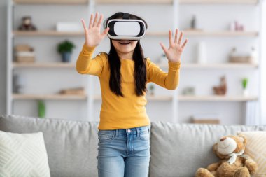 Gözlük takan, görünmez bir şeye dokunan neşeli bir genç kız.