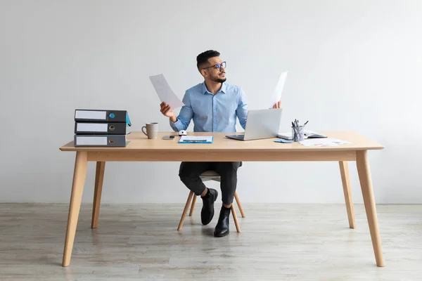 Uomo in possesso di un rapporto di lettura della carta che lavora su laptop in ufficio — Foto Stock
