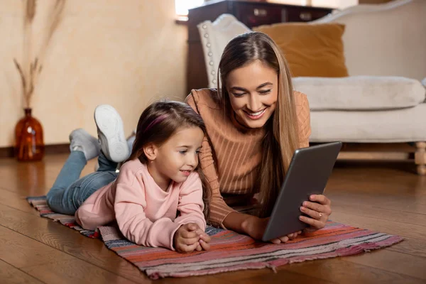 Usmívající se žena a dívka pomocí tablet doma — Stock fotografie