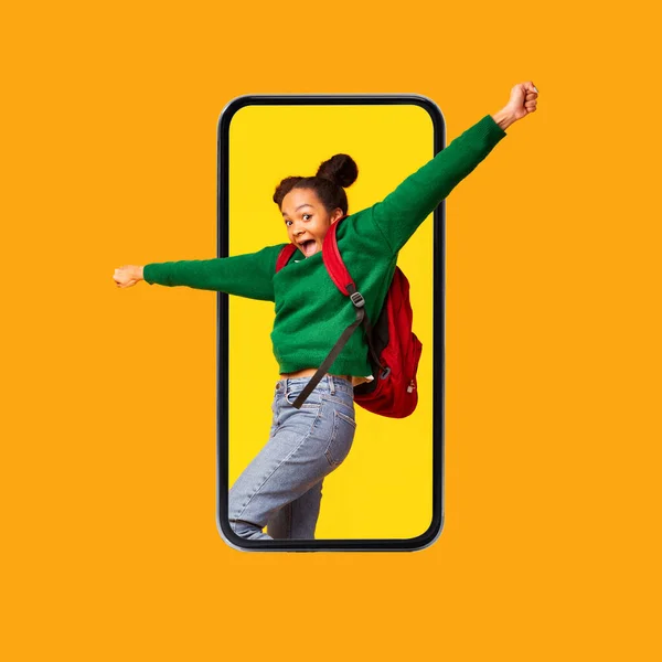 Podekscytowana czarna nastolatka krzyczy na ekranie telefonu komórkowego, pomarańczowe tło — Zdjęcie stockowe