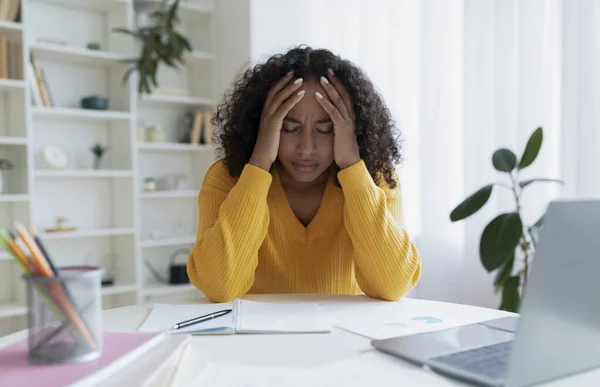 Terminstress. Erschöpfte junge schwarze Frau fühlt sich nach der Arbeit am Laptop müde und hat Kopfschmerzen zu Hause — Stockfoto