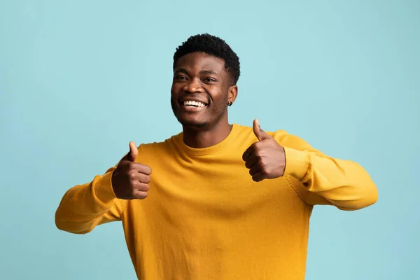 Roztomilý černošky chlap ukazující palec nahoru, pózování na modrém pozadí — Stock fotografie