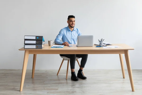 Uomo arabo che utilizza computer portatile seduto alla scrivania in ufficio — Foto Stock