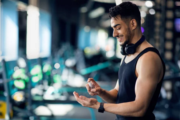 Sporty Arab Man Applying Disinfectant Spray On Hands Before Training At Gym — Stock Photo, Image