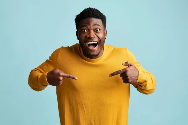 Сміється чорний хлопець вказує на його жовтий светр — стокове фото