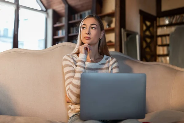 Mulher pensativa trabalhando no laptop em casa — Fotografia de Stock