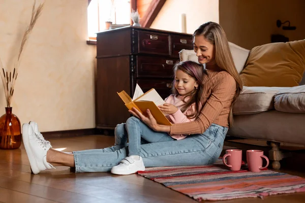 Porträtt av lycklig mor och dotter läser bok — Stockfoto