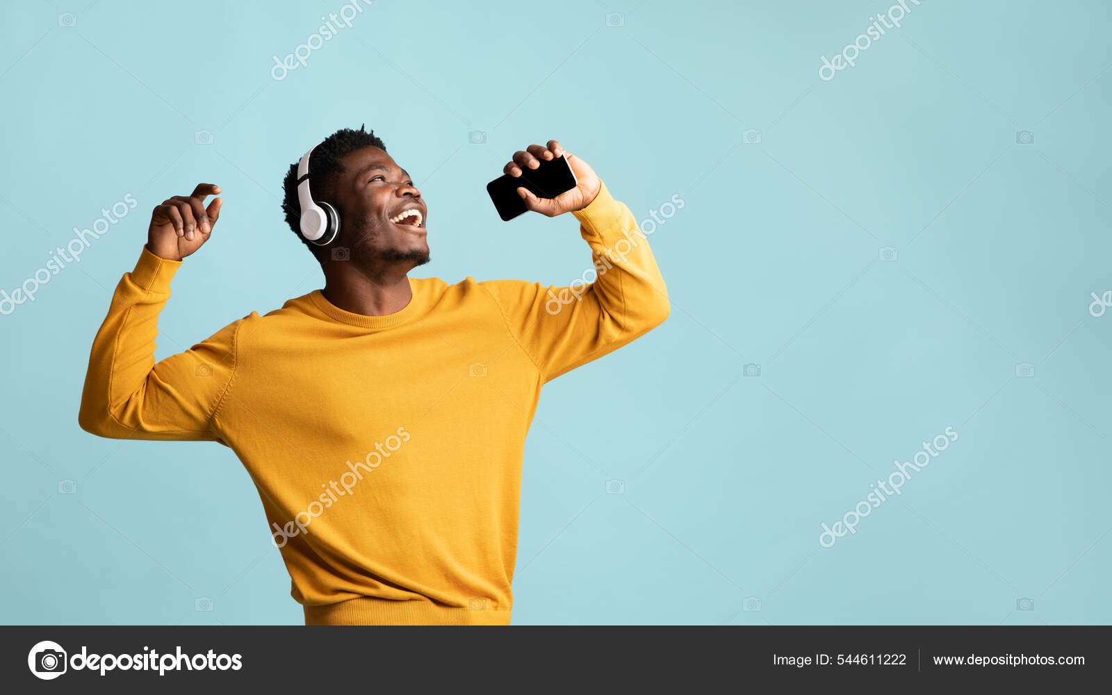 Радостный Черный Парень Поет Песни, Используя Наушники И Смартфон.