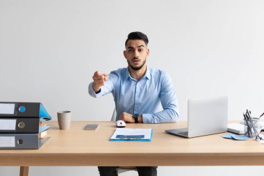 Arap adam dizüstü bilgisayarını kullanarak kamerayı işaret ediyor.