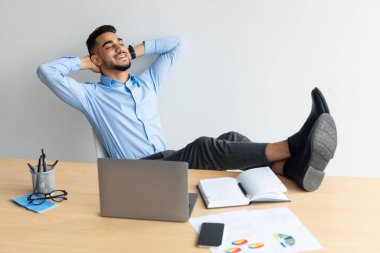 Gülümseyen bir Arap masaya yaslanıyor.