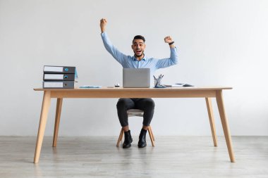 Heyecanlı adam dizüstü bilgisayar kullanarak başarıyı kutluyor, yumruklarını sallıyor ve evet diyor.