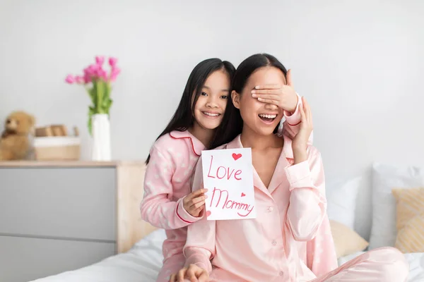 Довольная китайская девочка-подросток закрывает глаза на то, как молодая леди дает открытку и поздравляет с Днем матери — стоковое фото