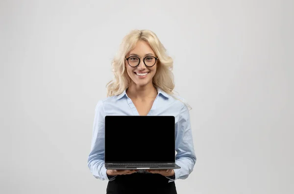 Ευτυχισμένη νεαρή επιχειρηματίας κρατώντας φορητό υπολογιστή με κενή οθόνη για τη διαφήμιση ή το σχεδιασμό της ιστοσελίδας σας — Φωτογραφία Αρχείου