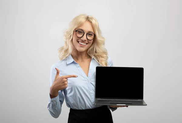 Empreendedora mulher feliz apontando para o computador portátil com tela em branco para o design do site no fundo do estúdio de luz — Fotografia de Stock