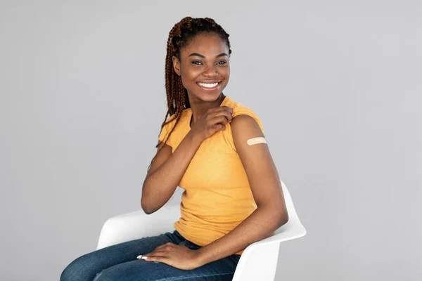 Afroamerikanerin lächelt nach Coronavirus-Impfung auf grauem Studiohintergrund — Stockfoto