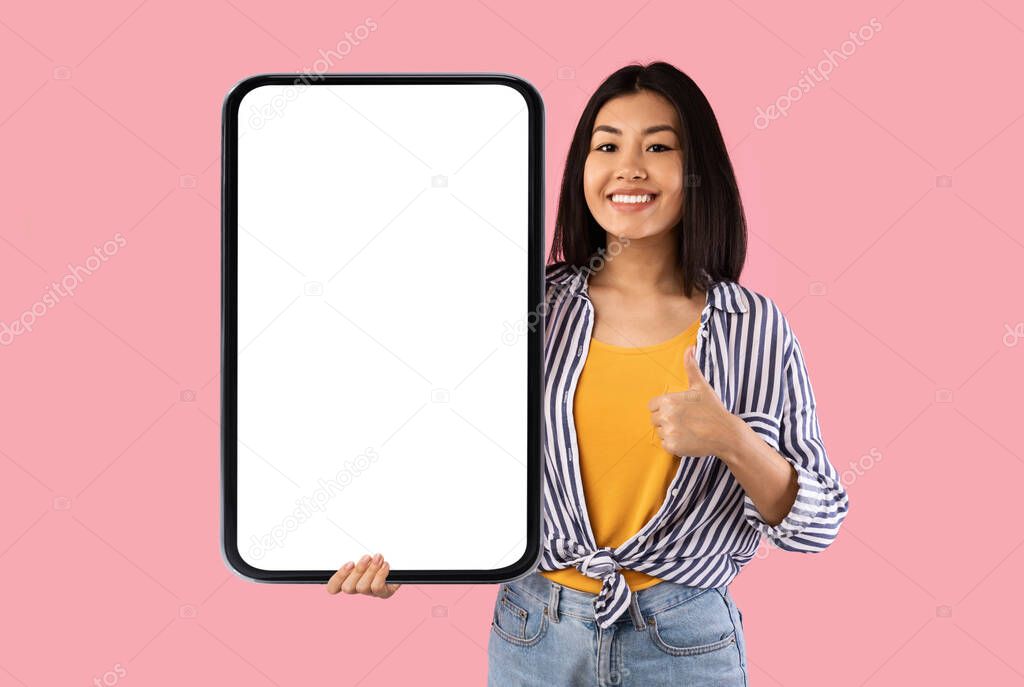 Japanese Woman Holding Huge Phone Blank Screen Gesturing Thumbs-Up, Studio