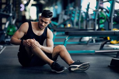 Spor Travması. Genç Arap erkek sporcu spor salonunda yaralı dizine dokunuyor.