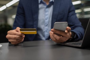 Akıllı telefon kullanan, kredi kartı tutan bir girişimci.
