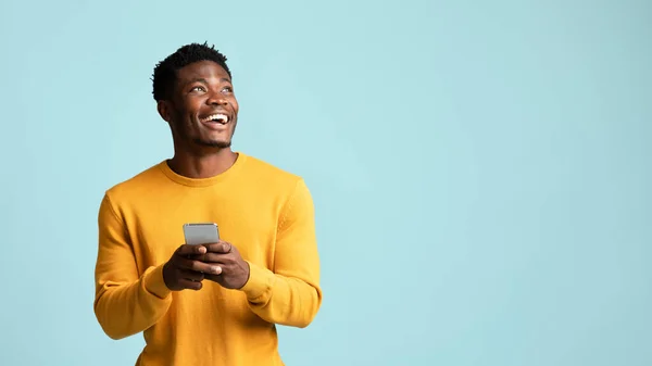 Homem negro alegre usando smartphone, olhando para o espaço de cópia — Fotografia de Stock