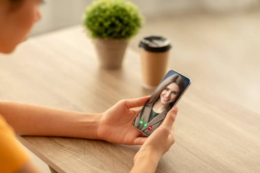 Mesafe iletişimi. Genç bir kadın kafeden cep telefonuyla sohbet ediyor, masada oturuyor.
