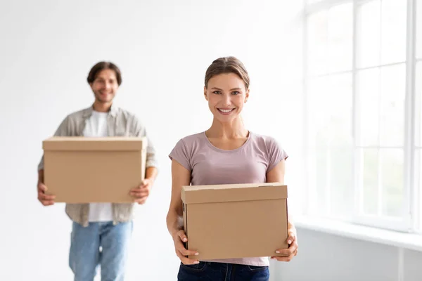 Щасливі тисячоліття європейські чоловіки і жінки носять коробки з речами, насолоджуються переїздом в нову квартиру — стокове фото