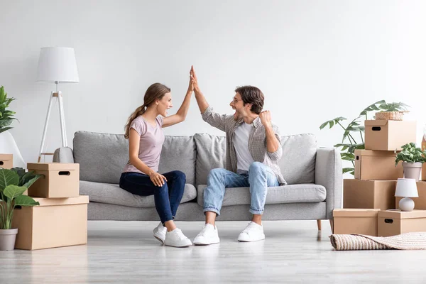 Felice uomo caucasico e signora che festeggiano l'acquisto di un nuovo appartamento dare cinque sedersi sul divano in camera interna — Foto Stock