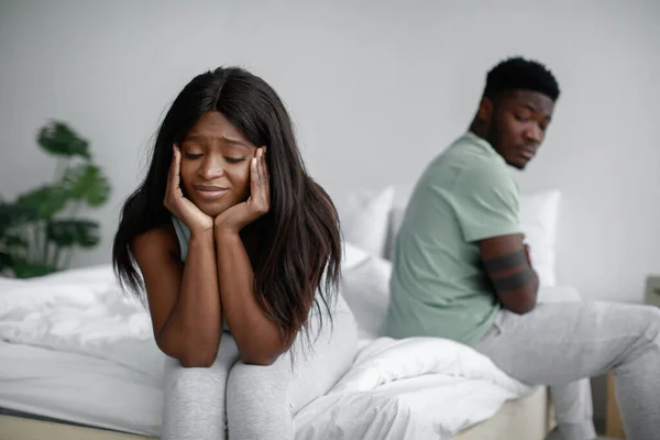 Despaired sad millennial black female ignoring offended male after quarrel sitting on bed in bedroom interior — Stock Photo, Image