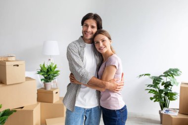 Binlerce yıllık Avrupalı erkek ve kadının kucaklaşması kutular ve bitkilerle dolu boş bir odada yeni dairenin tadını çıkarın.